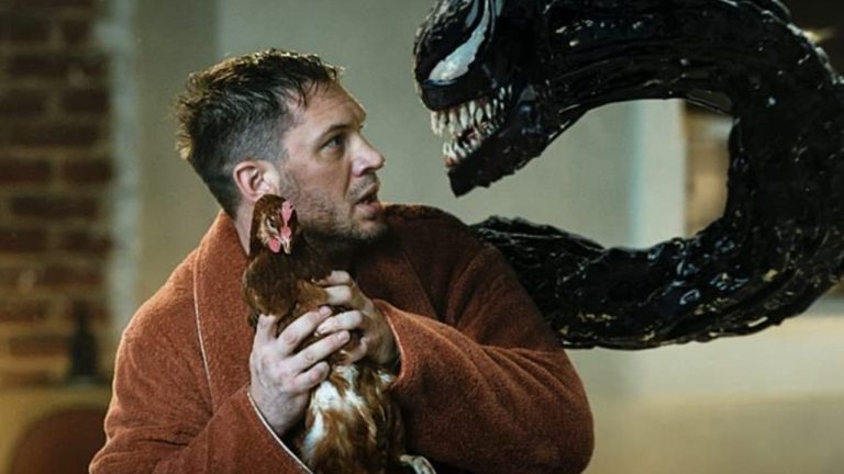 Tom Hardy em Venom, segurando uma galinha, enquanto o simbionte sai de seu corpo e o encara